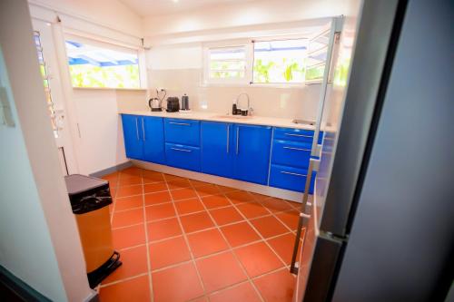 a kitchen with blue cabinets and a orange tile floor at Nature Paradise Pool & Spa - Exceptional Secluded Luxury Location in Le Diamant