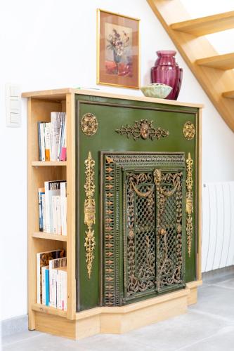 a green fireplace in a room with a book shelf at Au four et au jardin in Namur