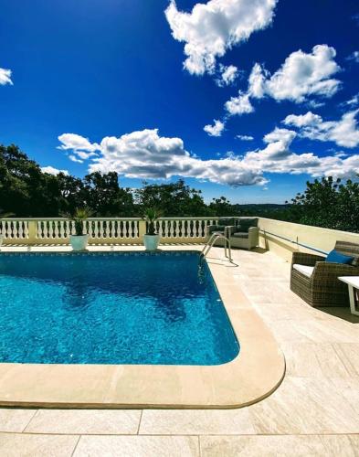 a swimming pool on a patio with a blue sky at Villa Panoramic Paradise in São Brás de Alportel