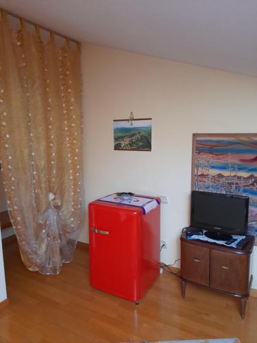 a room with a red refrigerator and a television at La mansarda di Daniela in Montepulciano Stazione