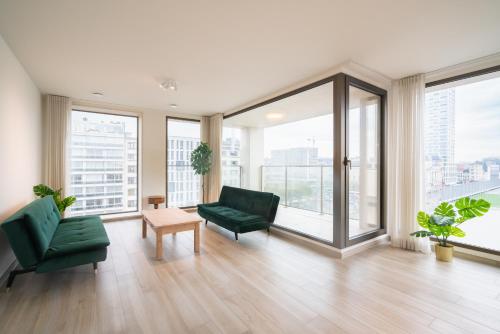 a living room with green furniture and large windows at Opera Square Apartments in the Center of Antwerp in Antwerp