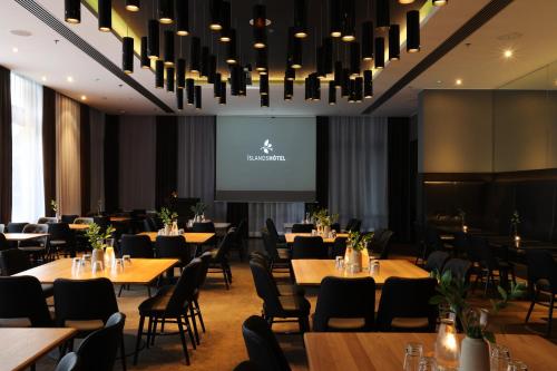 a dining room with tables and chairs and a projection screen at Hotel Reykjavík Grand in Reykjavík