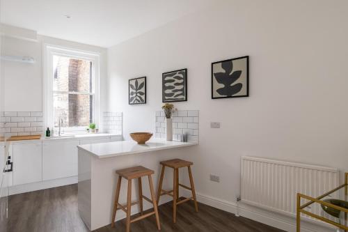 a kitchen with a counter and two stools at The Fulham Secret - Classy 5BDR Apartment in London
