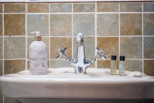 a sink with a bottle of soap and a soap dispenser at Taylors Townhouse in Royal Tunbridge Wells