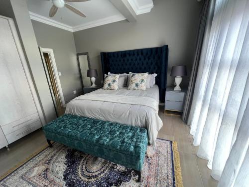 a bedroom with a large bed with a green bench at Sasavona Cottage - 349 Vaal de Grace Golf Estate in Parys