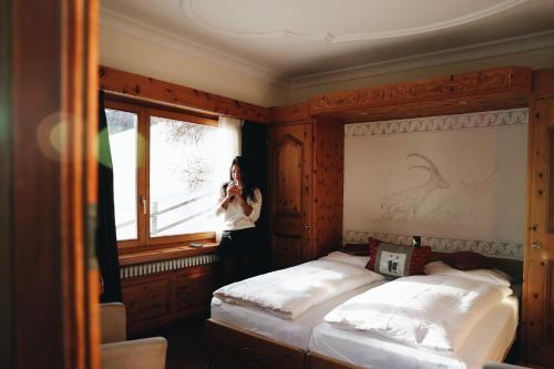 une femme prenant une photo d'une chambre avec deux lits dans l'établissement Hotel Nolda, à Saint-Moritz