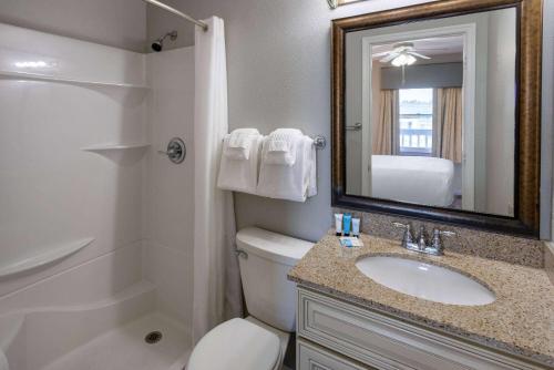 a bathroom with a toilet and a sink and a mirror at Sea Mystique Resort in Myrtle Beach