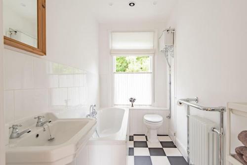 a white bathroom with a tub and a toilet and a sink at Poplar Farm House in Kent