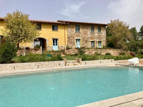 a swimming pool in front of a house at Agriturismo Is Conchisceddas in Gonnosfanàdiga
