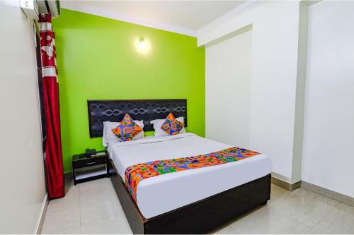 1 dormitorio con 1 cama con pared verde en FabExpress Ivory Pearl, en Bangalore
