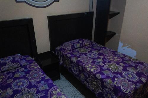 two beds in a room with purple sheets at OYO Hotel Colón, Plaza Bicentenario, Zacatecas Centro in Zacatecas