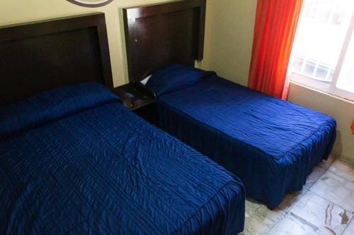 two beds in a hotel room with blue sheets at OYO Hotel Colón, Plaza Bicentenario, Zacatecas Centro in Zacatecas