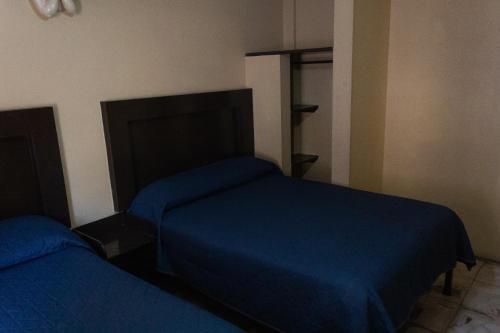 two beds in a room with blue sheets at OYO Hotel Colón, Plaza Bicentenario, Zacatecas Centro in Zacatecas