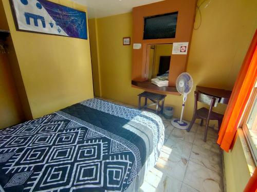 薩卡特卡斯的住宿－OYO Hotel Colón, Plaza Bicentenario, Zacatecas Centro，一间卧室配有一张床和一张带风扇的书桌