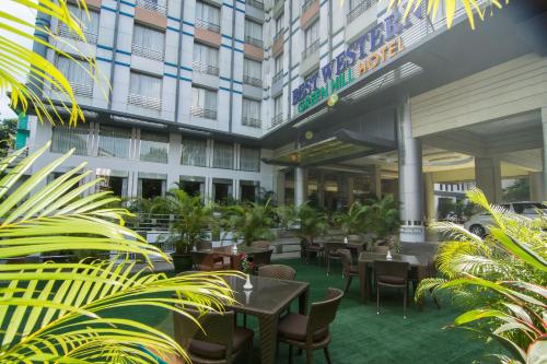 um pátio do hotel com mesas, cadeiras e plantas em Best Western Green Hill Hotel em Yangon