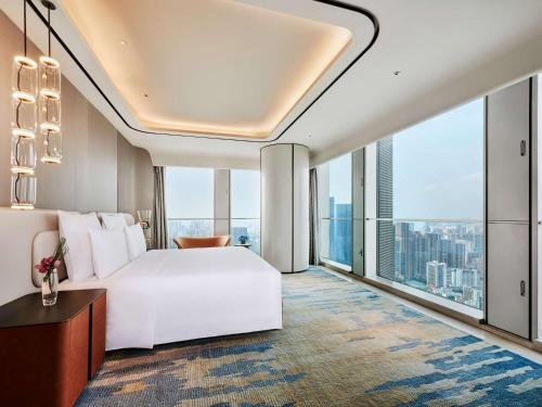 a bedroom with a white bed and large windows at Pullman Shenzhen North in Shenzhen