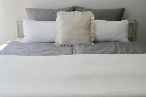 a white bed with four pillows on top of it at American Ease Apartments - Hahnbach, Vilseck, Weiden in Hahnbach
