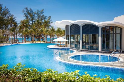 a swimming pool in front of a building with a resort at Best Western Premier Sonasea Phu Quoc in Phu Quoc