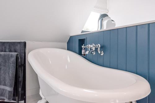 a white bath tub in a bathroom with blue tiles at Little Honey Pot in Saxmundham