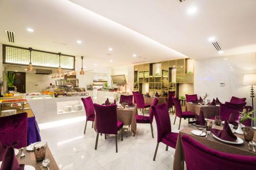 un restaurante con mesas y sillas de color púrpura y una cocina en Best Western Chinatown Hotel en Yangón