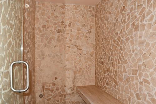 a bathroom with a shower with a stone wall at Ceren Luxury Apartments at Fifth Avenue by Spot Rentals in Playa del Carmen