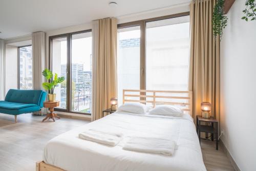 a bedroom with a white bed and a blue chair at Opera Square Apartments in the Center of Antwerp in Antwerp