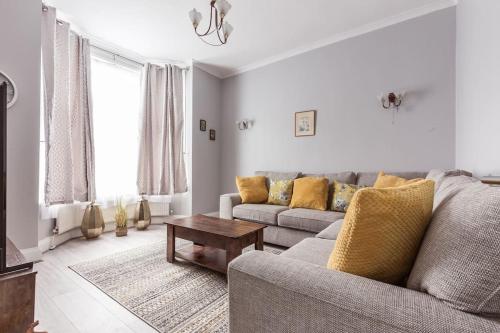 a living room with a couch and a table at 4 bedroom house, 2 Min Walk From Station in London