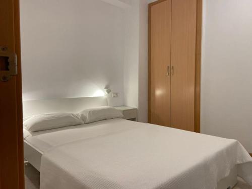 białe łóżko w sypialni z szafką w obiekcie Relax en primera linea B w mieście El Campello