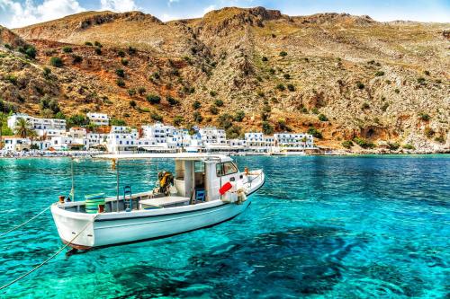 a boat in the water in front of a village at Traditional Villa Askyfou in Karés