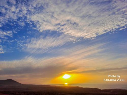a sunset over the ocean with a cloudy sky at Apartamentos EL BARCO in Sidi Ifni