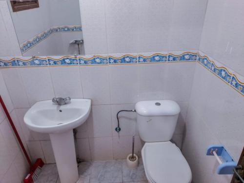 a bathroom with a white toilet and a sink at Apartamentos EL BARCO in Sidi Ifni