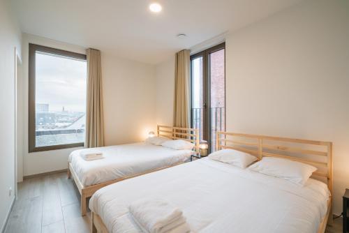 two beds in a room with a large window at Opera Square Apartments in the Center of Antwerp in Antwerp