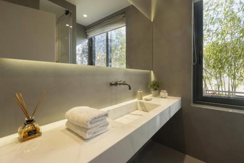 ein Bad mit einem Waschbecken und einem Spiegel in der Unterkunft Elegant, Chic, Hip 2 BR w/ forest view in Athens! in Athen