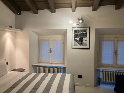 a bedroom with a bed and two windows at CUTE AND COZY CENTRO CITTA' in Bergamo