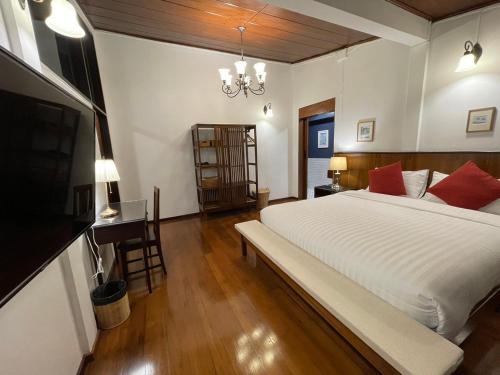 a bedroom with a large white bed and a desk at Stay @ Na Maeping บ้านส่วนตัวริมแม่น้ำปิง in Chiang Mai