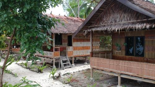 a house with a thatched roof and benches in front of it at Marine homestay in Fam