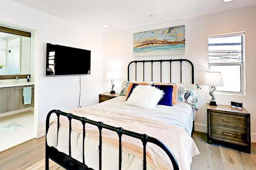 a bedroom with a large bed and a flat screen tv at Luxe Balboa Peninsula Condo w Gourmet Kitchen and Epic Rooftop Deck in Newport Beach