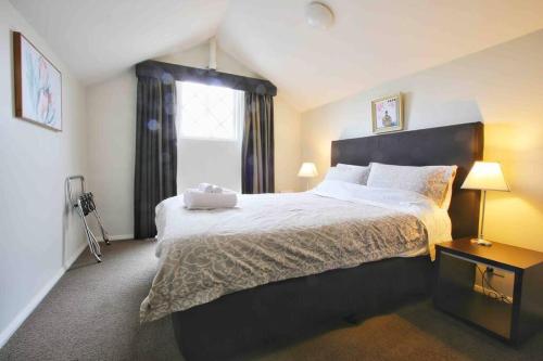 Central Hobart - Beautiful Apartment في هوبارت: غرفة نوم بسرير كبير ونافذة
