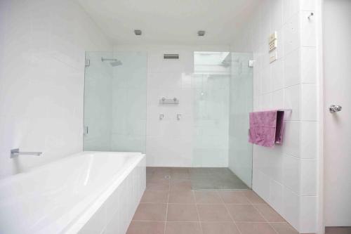 ホバートにあるCentral Hobart - Beautiful Apartmentの白いバスルーム(バスタブ、シャワー付)