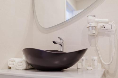 a bathroom with a black sink and a mirror at Muller Hotel Boutique & Spa in Galaţi