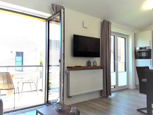 a living room with a television and a balcony at Nordlicht in Zingst