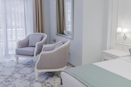 a bedroom with two chairs and a bed and a mirror at Muller Hotel Boutique & Spa in Galaţi