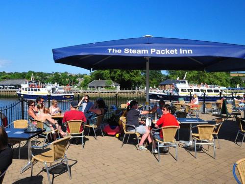 un grupo de personas sentadas en las mesas bajo un paraguas azul en The Steam Packet Inn, en Totnes