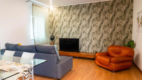 sala de estar con sofá, TV y silla en Pollicino House, en Caltagirone