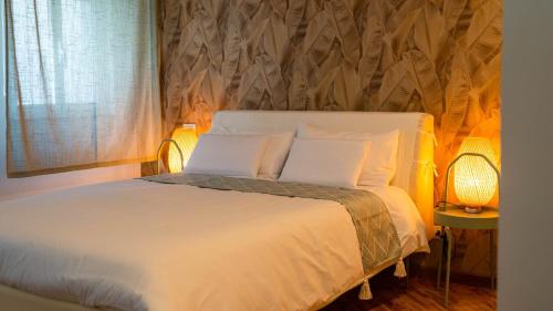 um quarto com uma cama branca, 2 candeeiros e uma janela em Pollicino House em Caltagirone