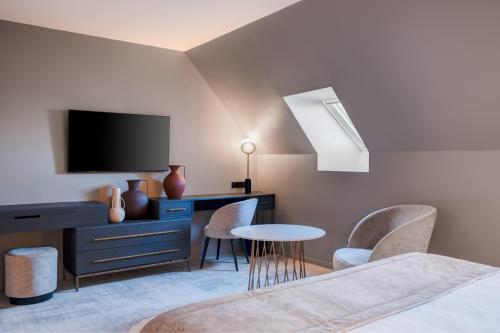 a bedroom with a tv and a desk and chairs at Fleur de Loire in Blois