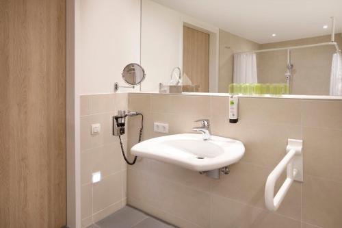 a bathroom with a sink and a mirror at Holiday Inn Frankfurt Airport by IHG in Frankfurt/Main