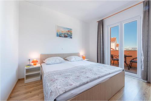 a white bedroom with a bed and a balcony at Apartments Mrkan in Cavtat