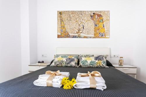 ein Schlafzimmer mit einem Bett mit Handtüchern und einem Gemälde in der Unterkunft -MalagaSunApts- City Centre SharedTerrace in Málaga