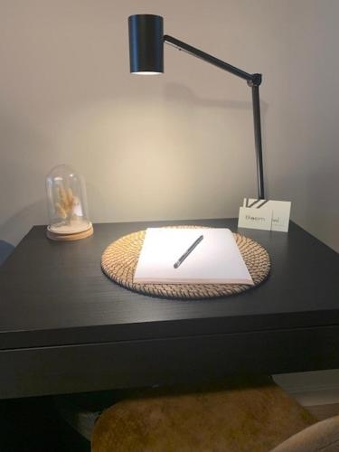 a desk with a lamp and a book on it at Bloomhotel in Lochristi